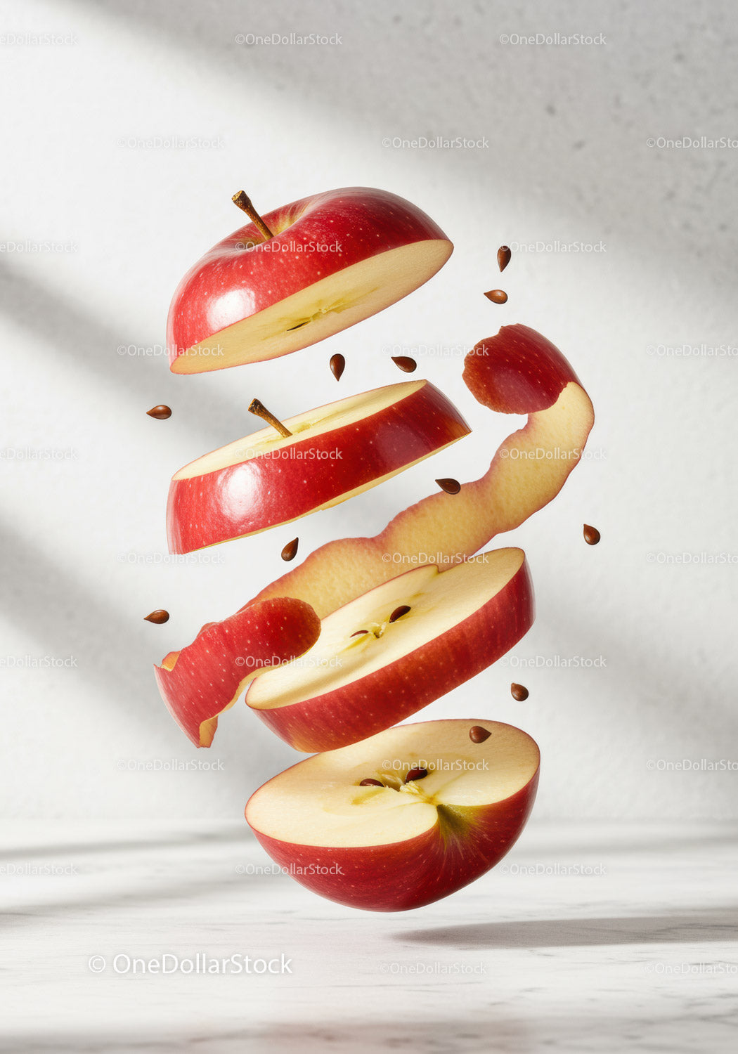 Floating sliced red apple with scattered seeds and peel