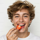 Joyful Teenage Boy Enjoying Fresh Strawberry with Bright Smile