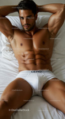 Muscular man lying on bed in white underwear