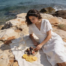 Woman enjoying figs and lemon slices by the sea