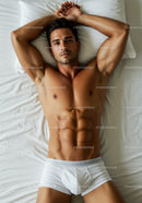 Fit young man relaxing on bed in white underwear