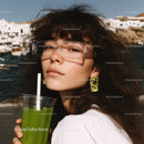 Young Woman with Wavy Hair Wearing Sunglasses Holding Green Smoothie