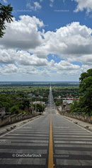 Long Asphalt Road Extending Toward Distant Horizon with Lush Greenery and Clouds
