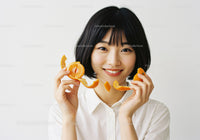 Young Woman Holding Fresh Tangerine and Orange Peel in Bright Studio