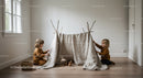 Two children building a cozy indoor fabric fort