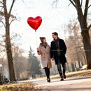 Couple walking outdoors holding heart-shaped balloon