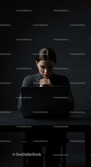 Thoughtful Woman at Laptop in Dark Modern Workspace