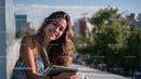 Smiling Young Woman with Curly Hair Using Tablet Outdoors in City