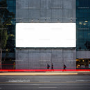 Urban street scene with large blank billboard at dusk