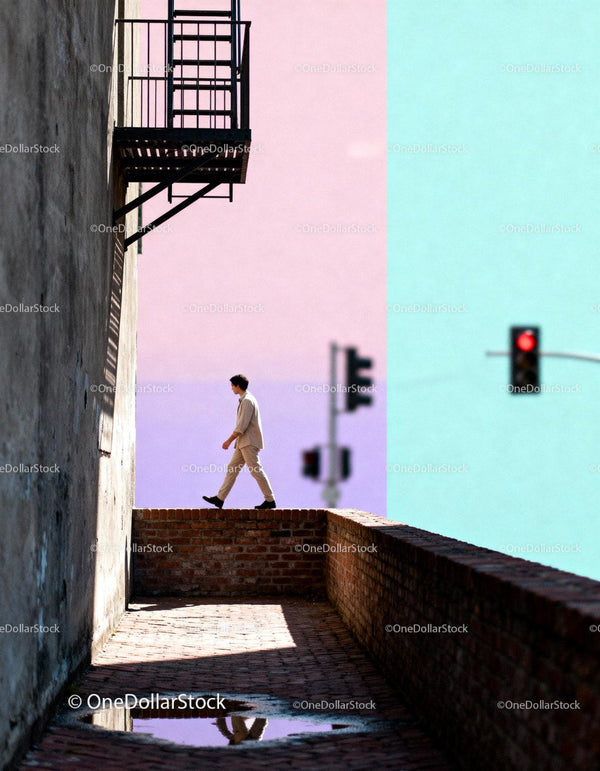 Man walking along urban brick wall with colorful sky