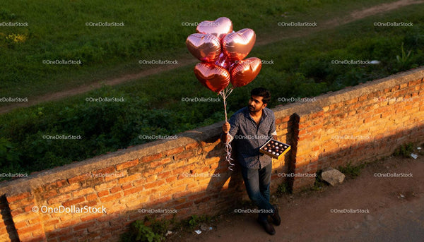 Man Holding Heart Balloons and Chocolates Outdoors