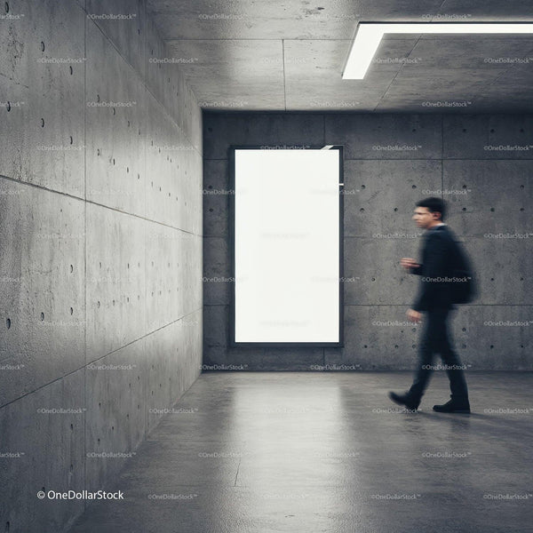 Man walking past illuminated blank poster in concrete corridor JPG Mockup Image
