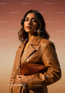 Elegant Woman in Brown Leather Coat with Handbag Under Sunset Light