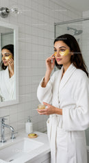 Woman Applying Gold Eye Patches in Bathroom for Skin Rejuvenation