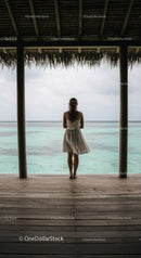 Woman Standing at a Tropical Beach Hut Overlooking Calm Ocean Horizon