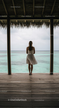Woman Standing at a Tropical Beach Hut Overlooking Calm Ocean Horizon