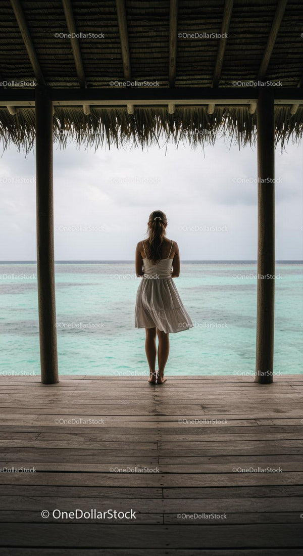 Woman Standing at a Tropical Beach Hut Overlooking Calm Ocean Horizon