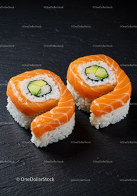 Fresh salmon avocado sushi rolls on black slate