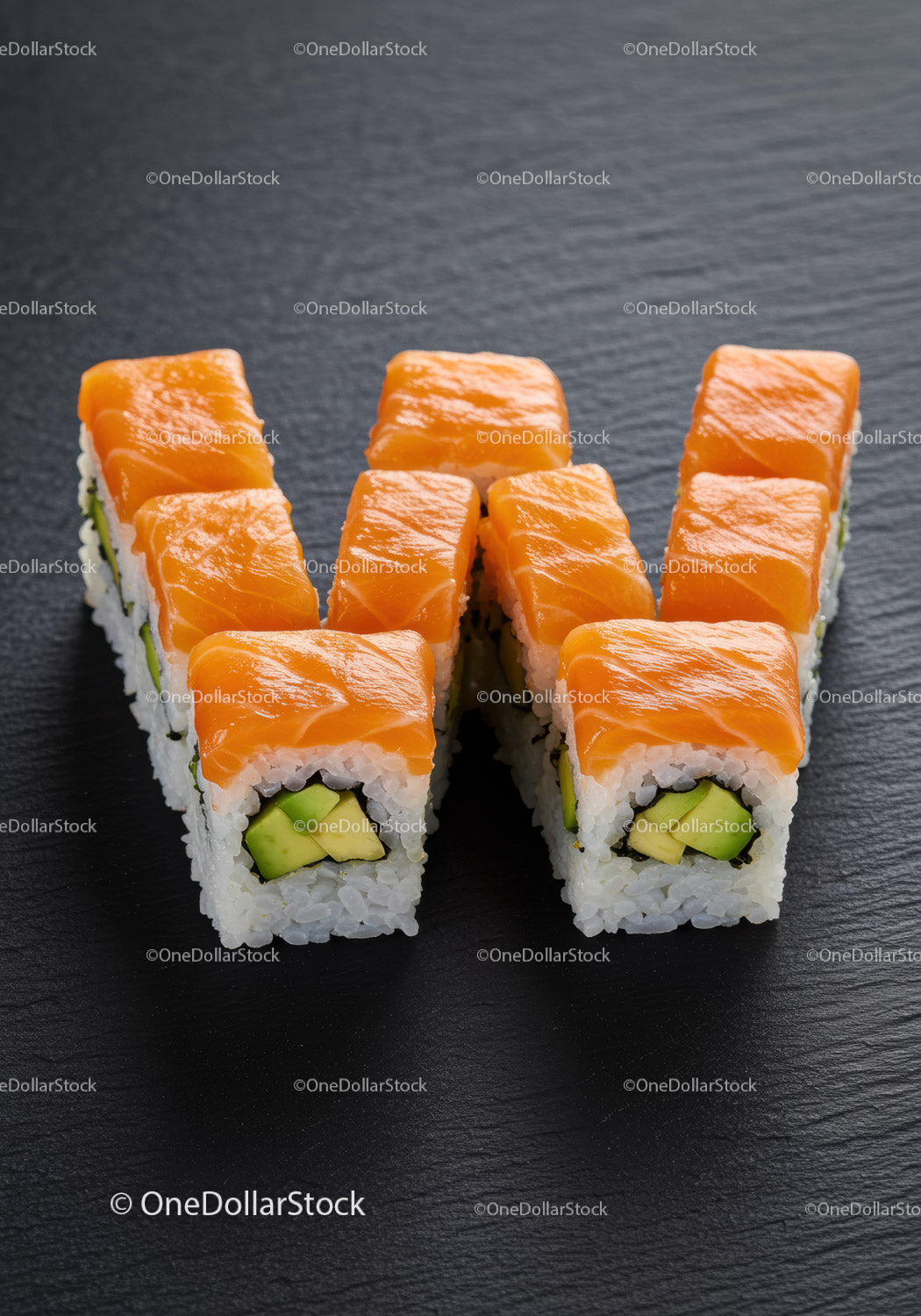 Świeże rolki sushi z łososiem i awokado na ciemnym talerzu łupkowym