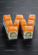 Fresh salmon avocado sushi rolls on dark slate plate