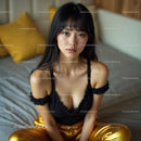 Young Woman in Black Top and Gold Pants Sitting in Cozy Bedroom