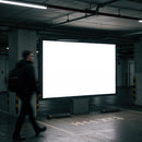 Man walking past illuminated blank billboard in parking garage
