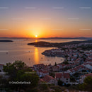 Serene Sunset Over Coastal Town with Red Roofs and Mountain Backdrop