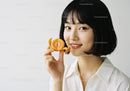 Young Woman Smiling with Orange Peel in Bright Studio Setting