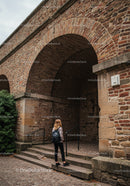 Historic Brick Archway with Cobblestone Path and Tourist Girl