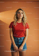 Young woman in red t-shirt and denim shorts posing indoors