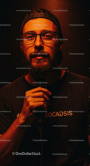 Man with beard and glasses holding microphone on dark background