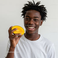 Young Man with Dreadlocks Holding Yellow Mango Smiling Fast