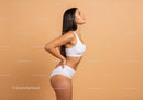 Athletic Woman in White Sportswear Posing Against Beige Background
