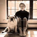 Calm woman sitting by window with English bulldog