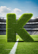 Large Grass Letter K on Soccer Field with Stadium Crowd