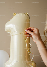 Hand Holding Gold Number One Balloon with Ribbon