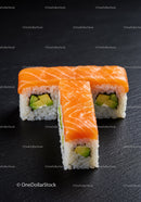 Fresh salmon sushi rolls with avocado on black surface