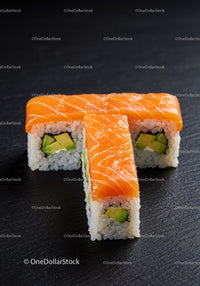 Fresh salmon sushi rolls with avocado on black surface