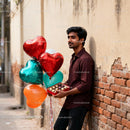 Man holding heart balloons and chocolates outdoors