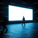 Silhouettes walking past bright urban billboard at night