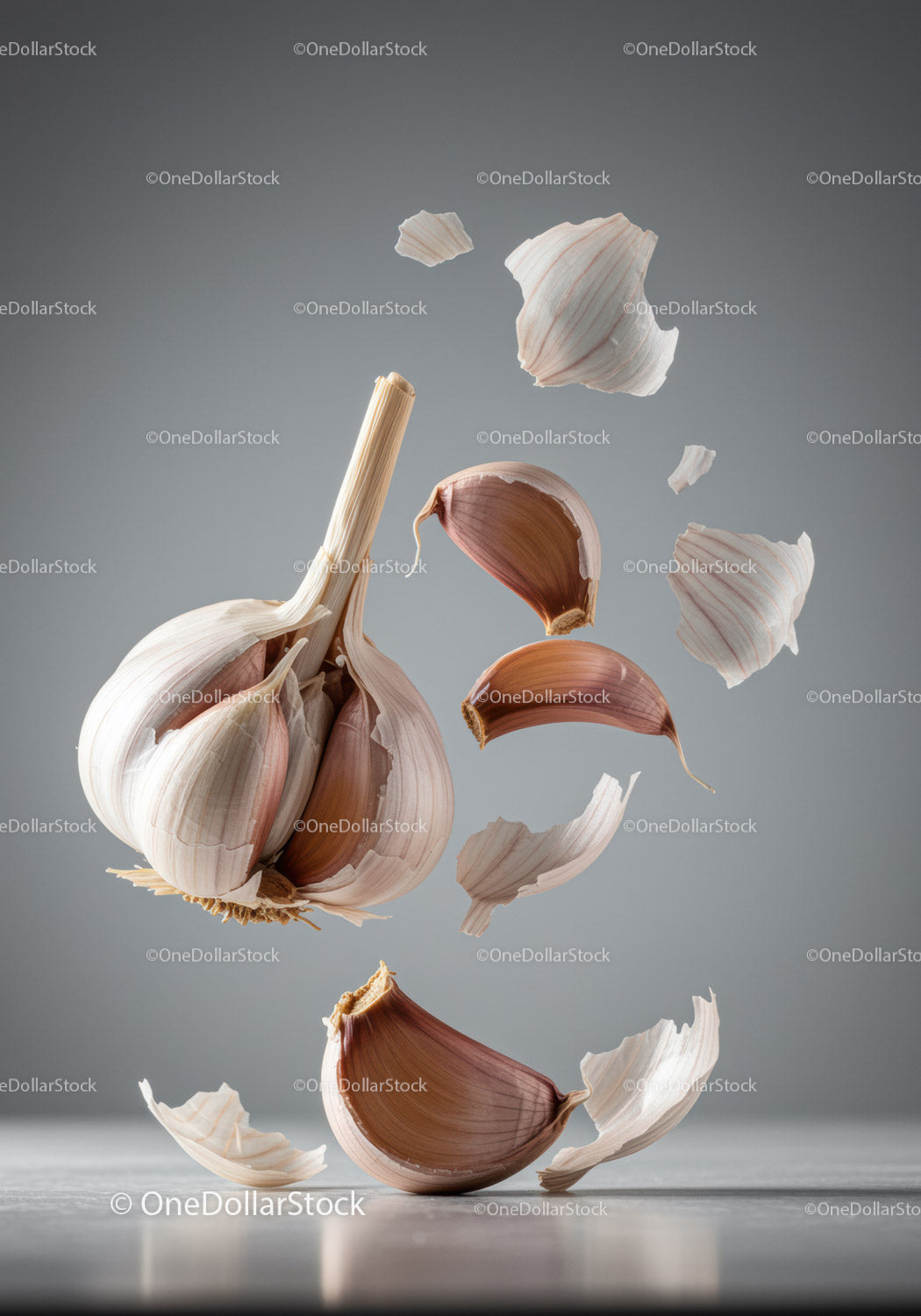 Floating garlic cloves with peeling skin on gray background