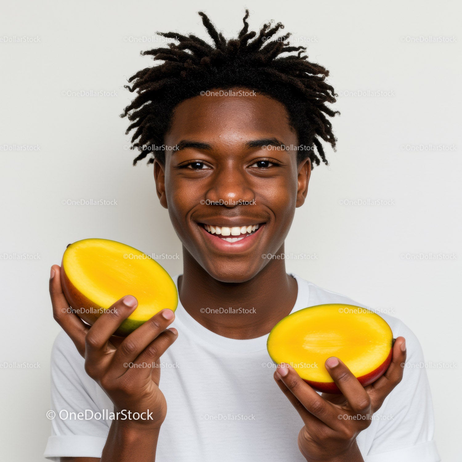 Młody mężczyzna trzymający świeże połówki mango w jasnym studiu