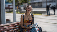 Young Woman Sitting on Park Bench Using Tablet in Urban Environment