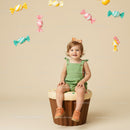 Smiling toddler sitting on cupcake with hanging candies