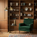 Cozy reading nook with green armchair and brass lamp