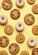 Assorted cookies and powdered donuts on yellow background