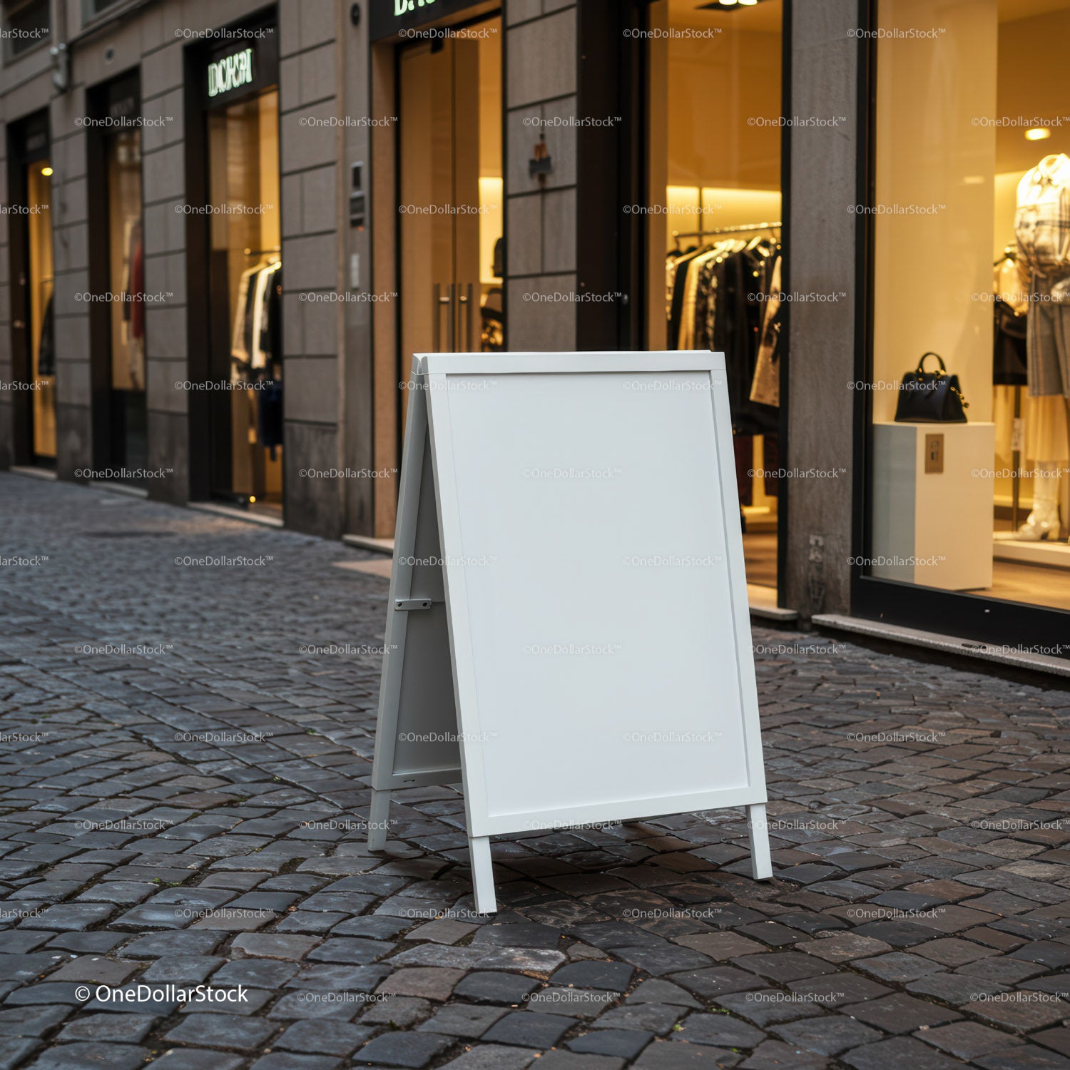 Blank white sidewalk sign on cobblestone street outside store