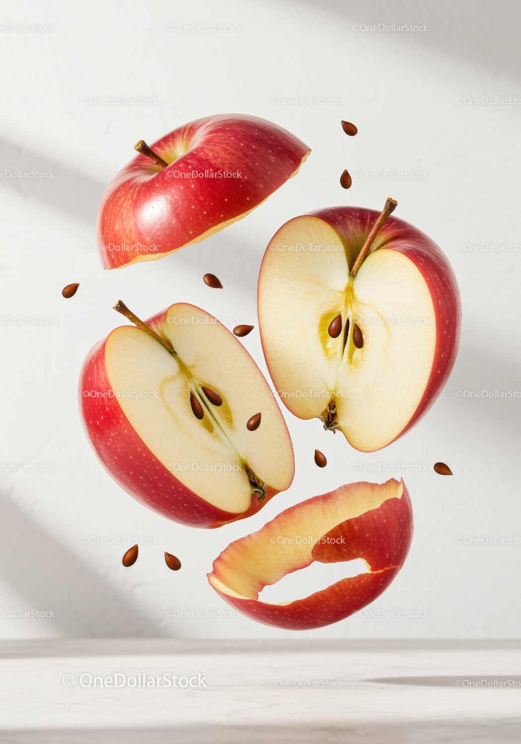 Fresh red apple slices with floating seeds on white