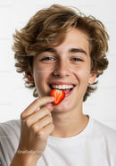 Happy Teen Smiling with Strawberry Fruit Snack in Bright Studio