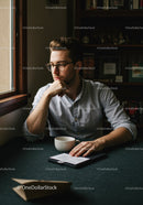 Young Man Reading Book and Drinking Coffee Indoors